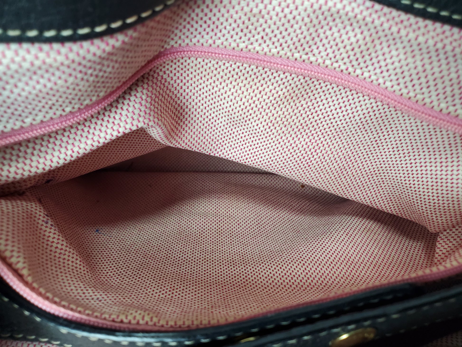 Close-up of a pink textured fabric interior with visible stitching.