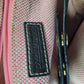 Close-up of a label on a pink textured fabric with gold accents.