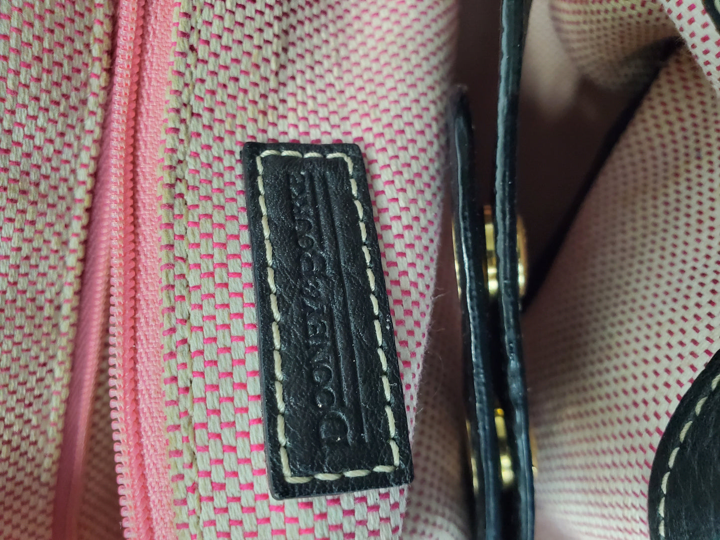 Close-up of a label on a pink textured fabric with gold accents.