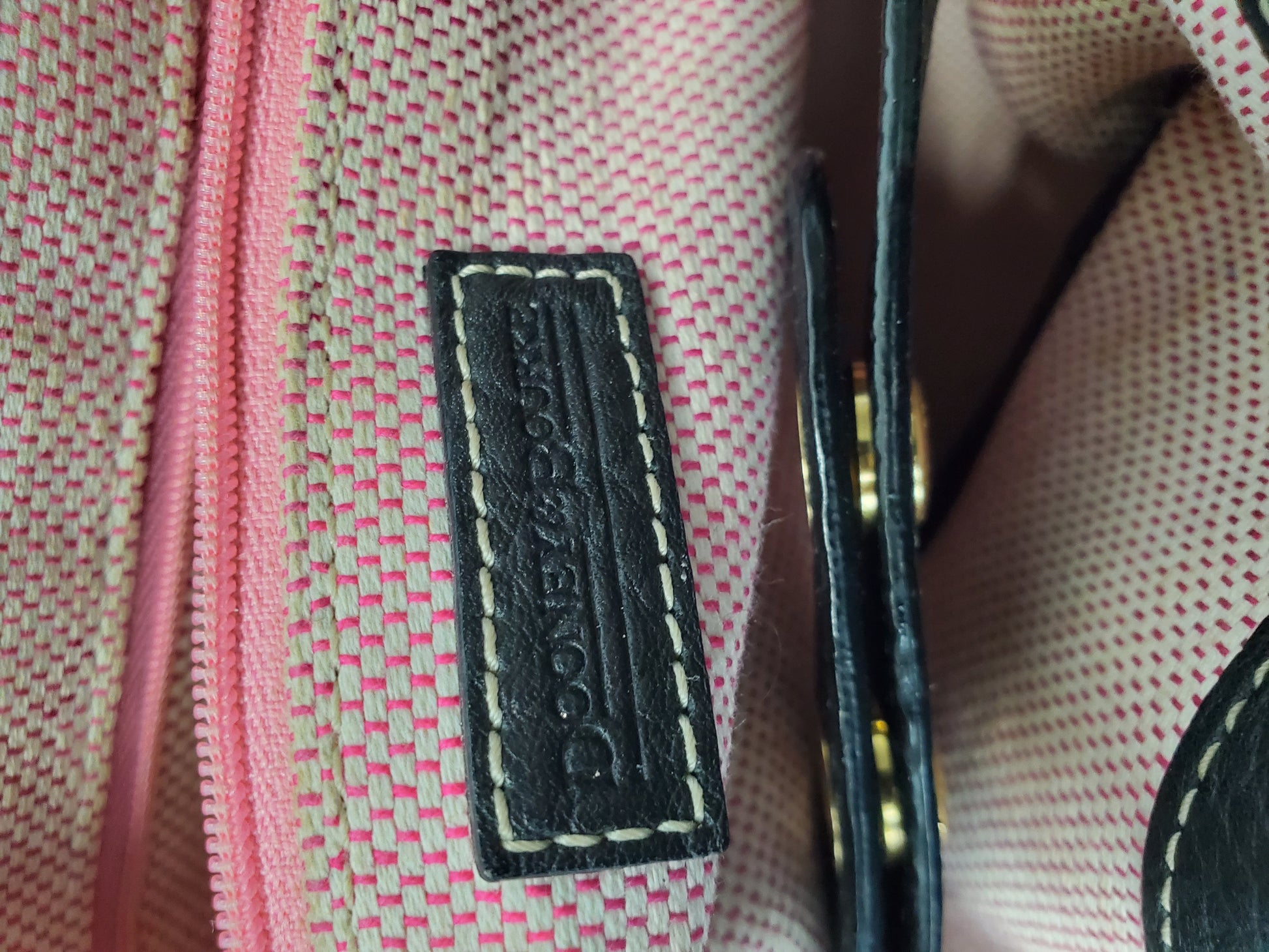 Close-up of a label on a pink textured fabric with gold accents.