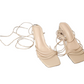 Pair of beige high-heeled shoes with tied laces on a white background