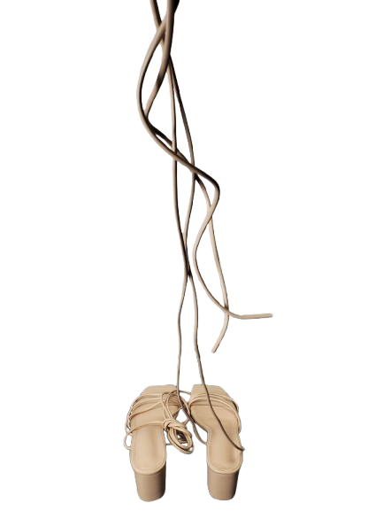 Pair of beige ballet shoes with ribbons on a white background