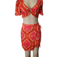 Mannequin wearing a red and pink patterned top and skirt set on a white background