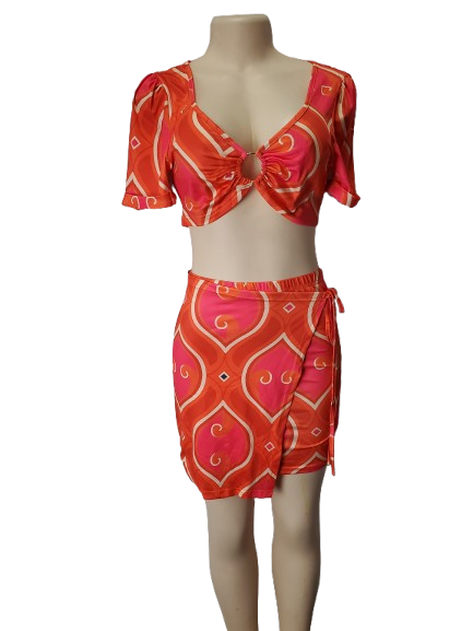 Mannequin wearing a red and pink patterned top and skirt set on a white background