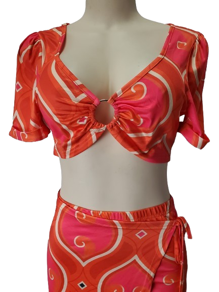 Orange and pink patterned top and skirt set on a mannequin against a white background