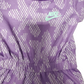 Purple athletic romper with white pattern and green logo on a white background