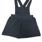 black pinafore dress with white polka dots on a white background