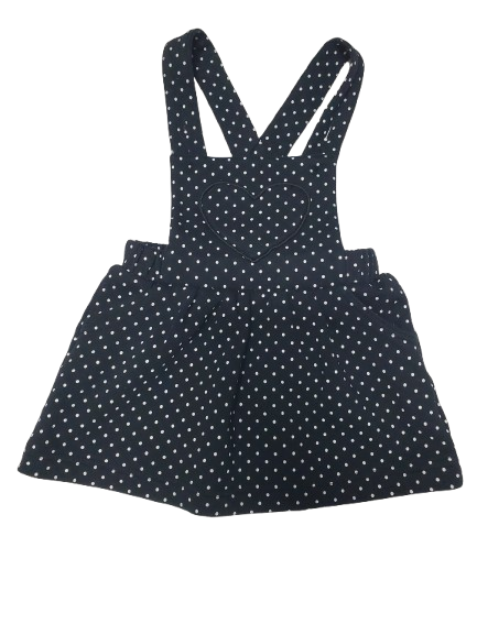 black pinafore dress with white polka dots on a white background