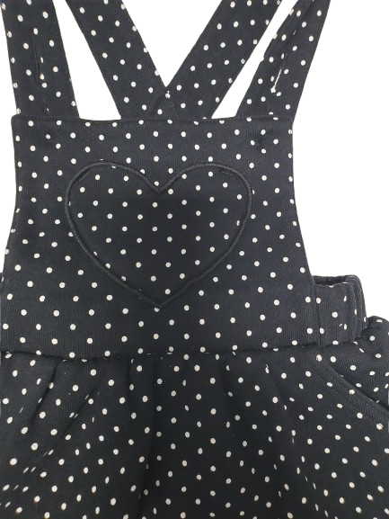 Black polka dot pinafore dress with a heart design on a white background