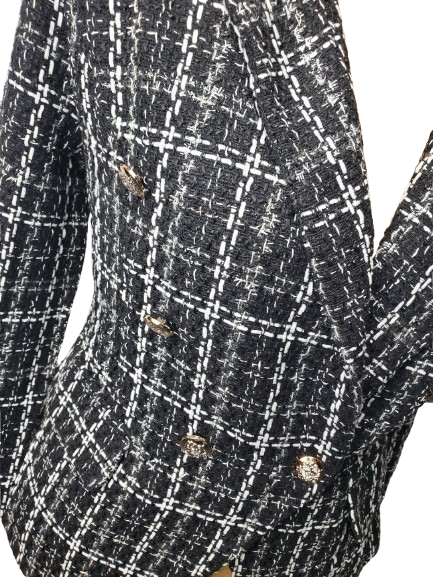 Close-up of a black and white checkered blazer with gold buttons on a white background