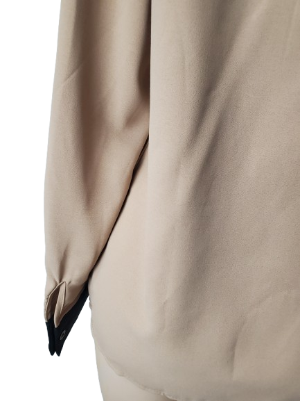 Close-up of a beige garment with a black trim on a white background
