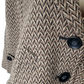 Close-up of a textured fabric with a herringbone pattern and black buttons.