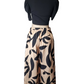 Mannequin wearing a black top and beige pants with black leaf pattern on a white background