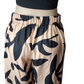 Beige pants with black leaf pattern worn by a person on a white background
