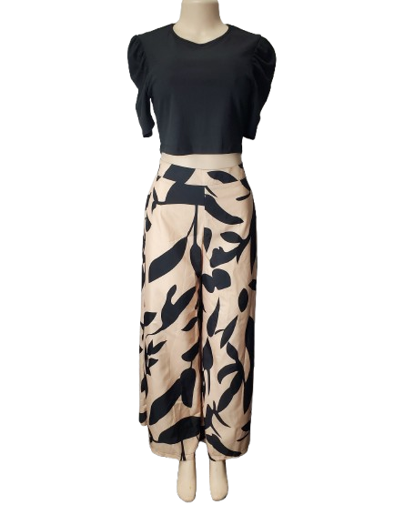 Mannequin wearing a black top and beige pants with black abstract pattern on a white background