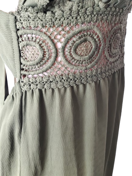 Close-up of a green dress with intricate crochet detailing on a white background