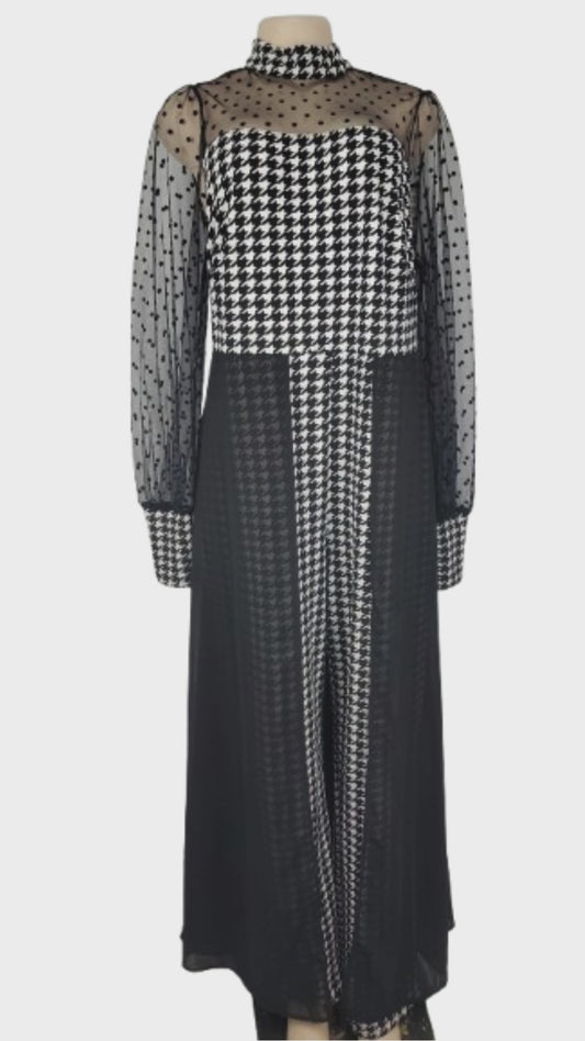 Black and white checkered jumpsuit with sheer sleeves on a mannequin against a white background