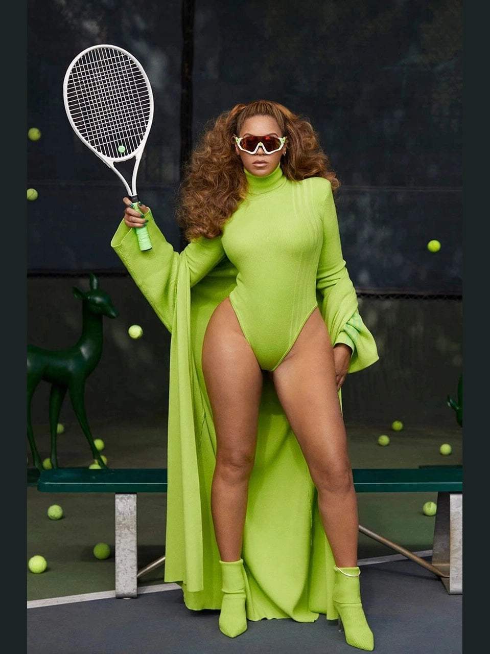Person in a bright green outfit holding a tennis racket on a tennis court with tennis balls scattered around.